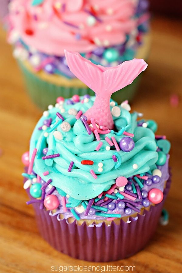 This image features a vibrant and whimsical cupcake, decorated with swirls of turquoise and pink frosting. Topping the frosting is a mermaid tail, adding to the under-the-sea theme. The cupcake is also adorned with colorful sprinkles, creating a fun and festive look. This design would be perfect for a mermaid-themed party or celebration!
