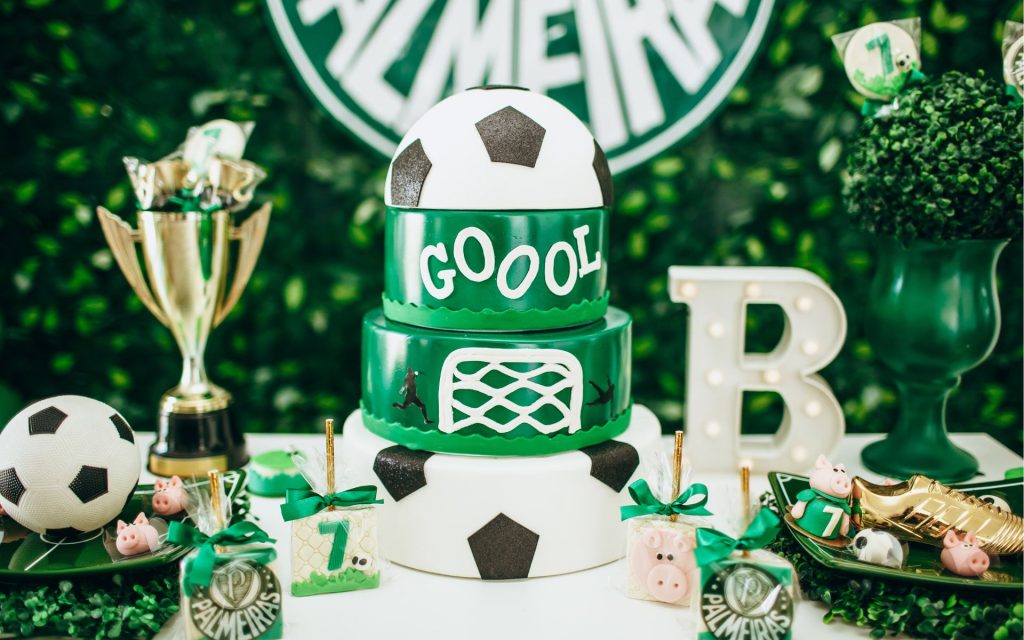 "A soccer-themed birthday party setup with a green and white tiered cake, football decorations, trophies, and custom party favors. A perfect example of planning children's parties with a fun sports theme."